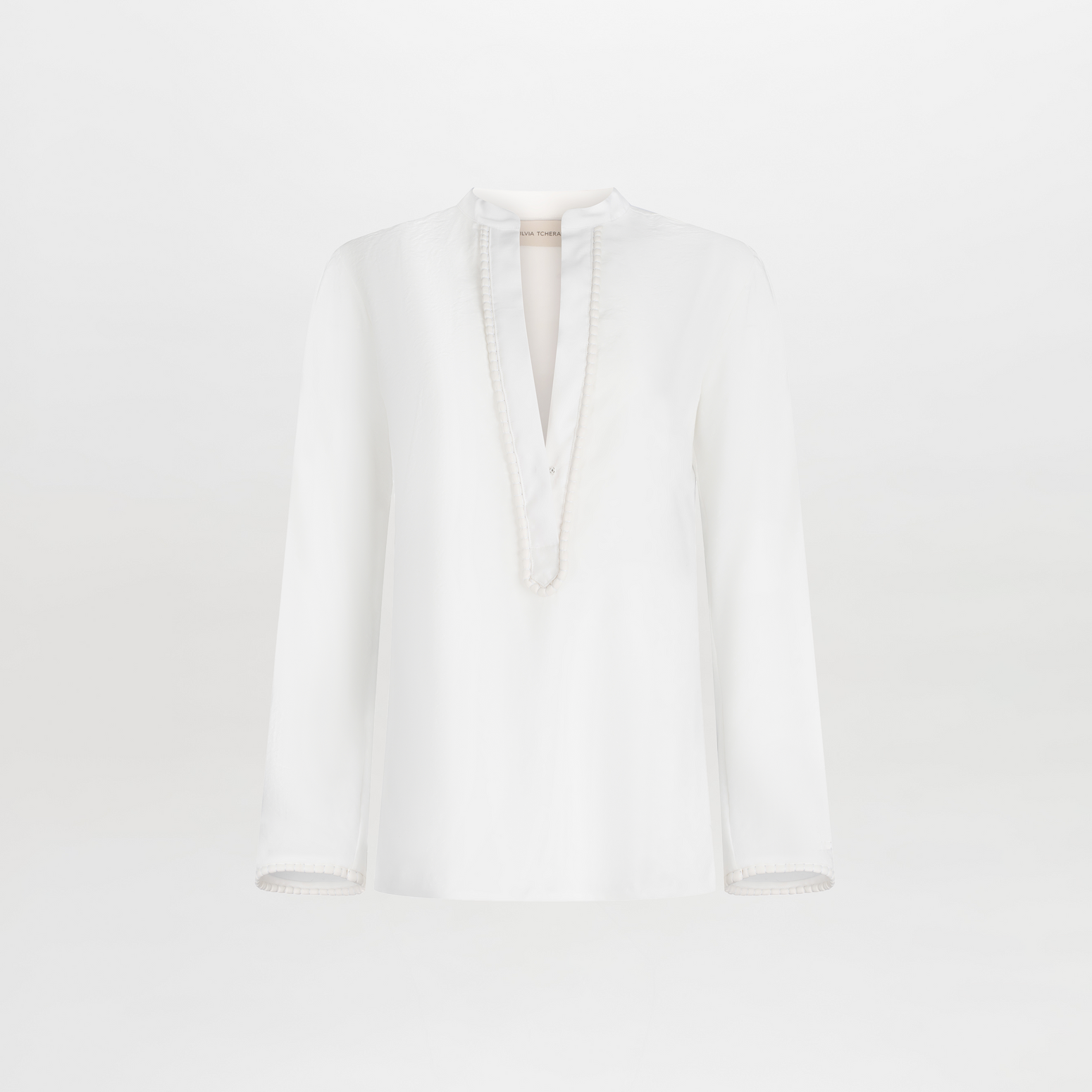 Shera Blouse White with a v-neckline and long sleeves, displayed on a plain background.