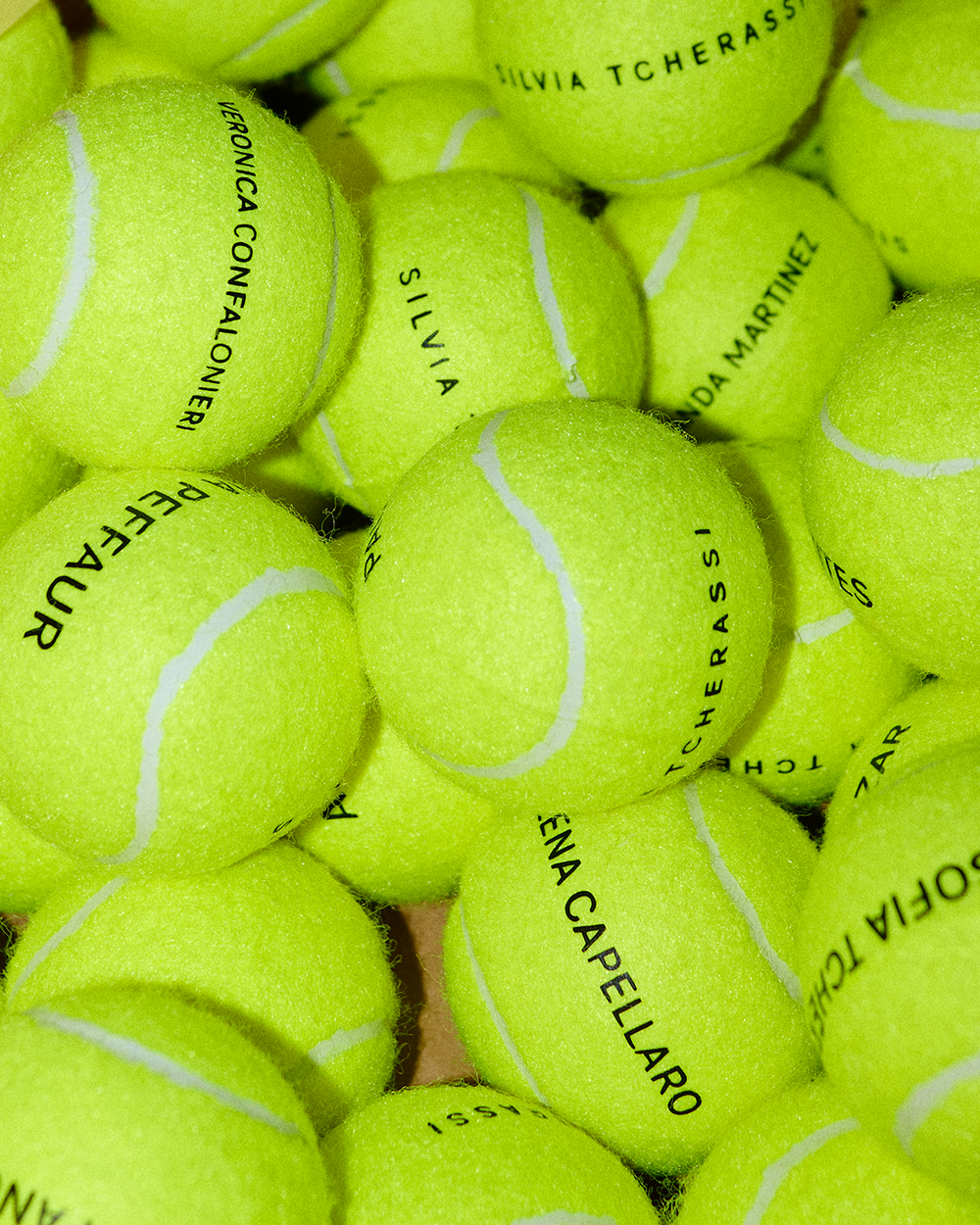 Stack of green tennis balls with names printed on them.