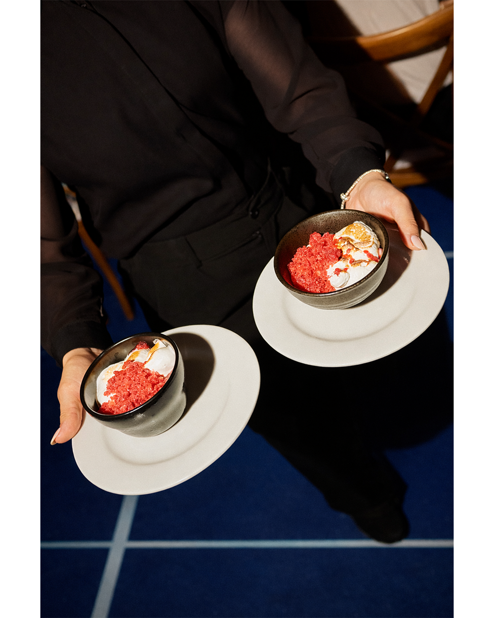 Two small bowls with red and white contents held by a person on a blue floor.