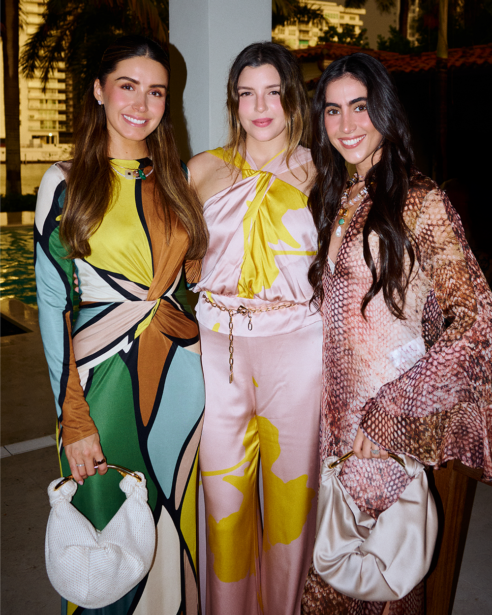 Three women posing together in stylish outfits with colorful patterns.