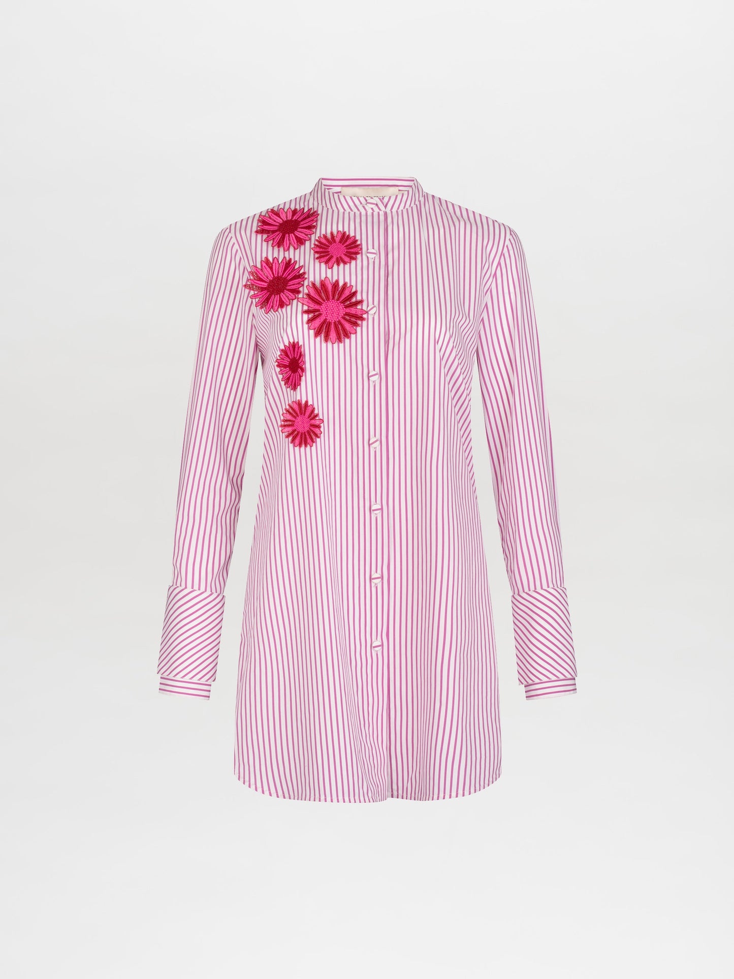 A person in the Silvina Blouse Rose Stripes adorned with floral appliqués, paired with a pink sequined skirt featuring similar floral designs, stands against a plain white background, available for pre-order now with an expected ship date in early 2025.