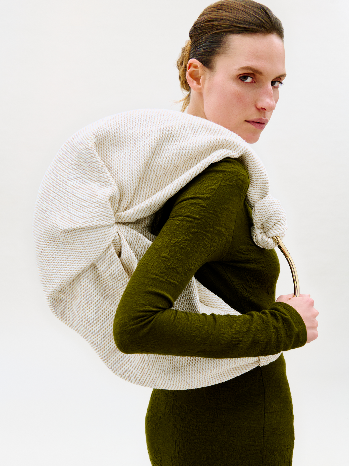 Woman wearing a white knitted shawl over her shoulders against a plain background