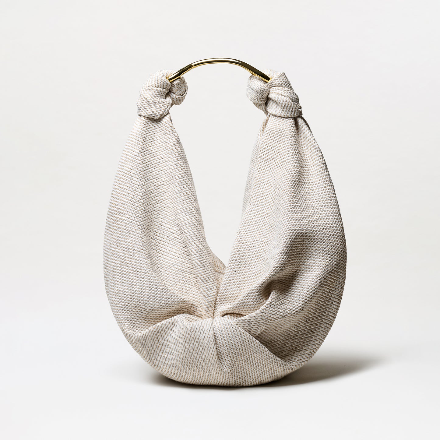 The Sofia Tennis Bag (Maxi) is a cream-colored, textured Italian-fabric bag with a soft, rounded shape and knotted handle accented by curved gold-tone hardware, shown against a plain white background.