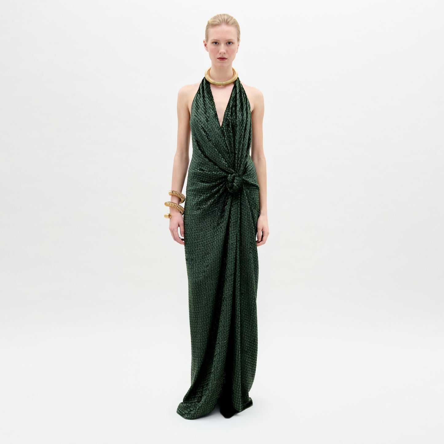 A woman wearing the Torgiano dress in color Hunter greenb with golden accesories on a white background.