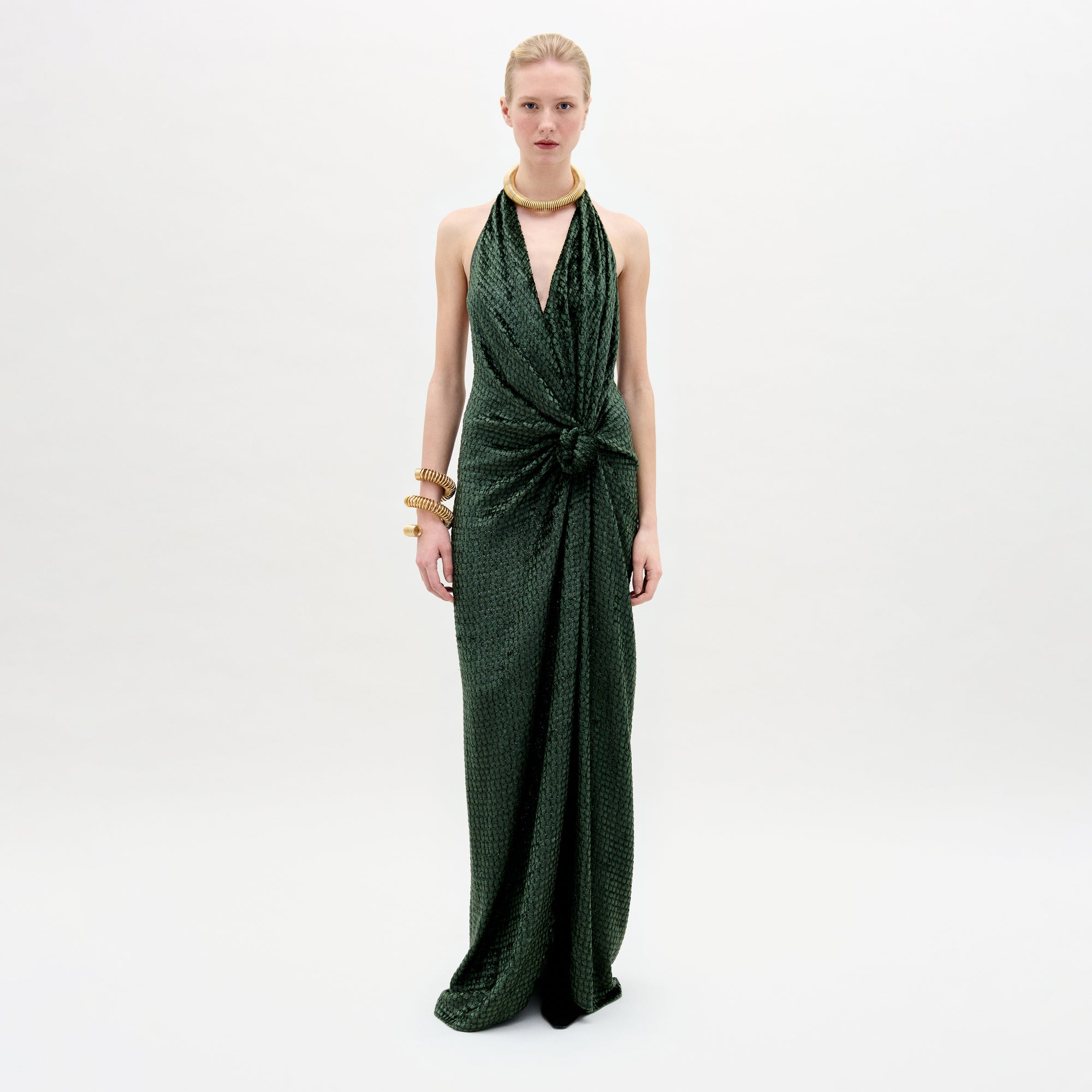 A woman wearing the Torgiano dress in color Hunter greenb with golden accesories on a white background.