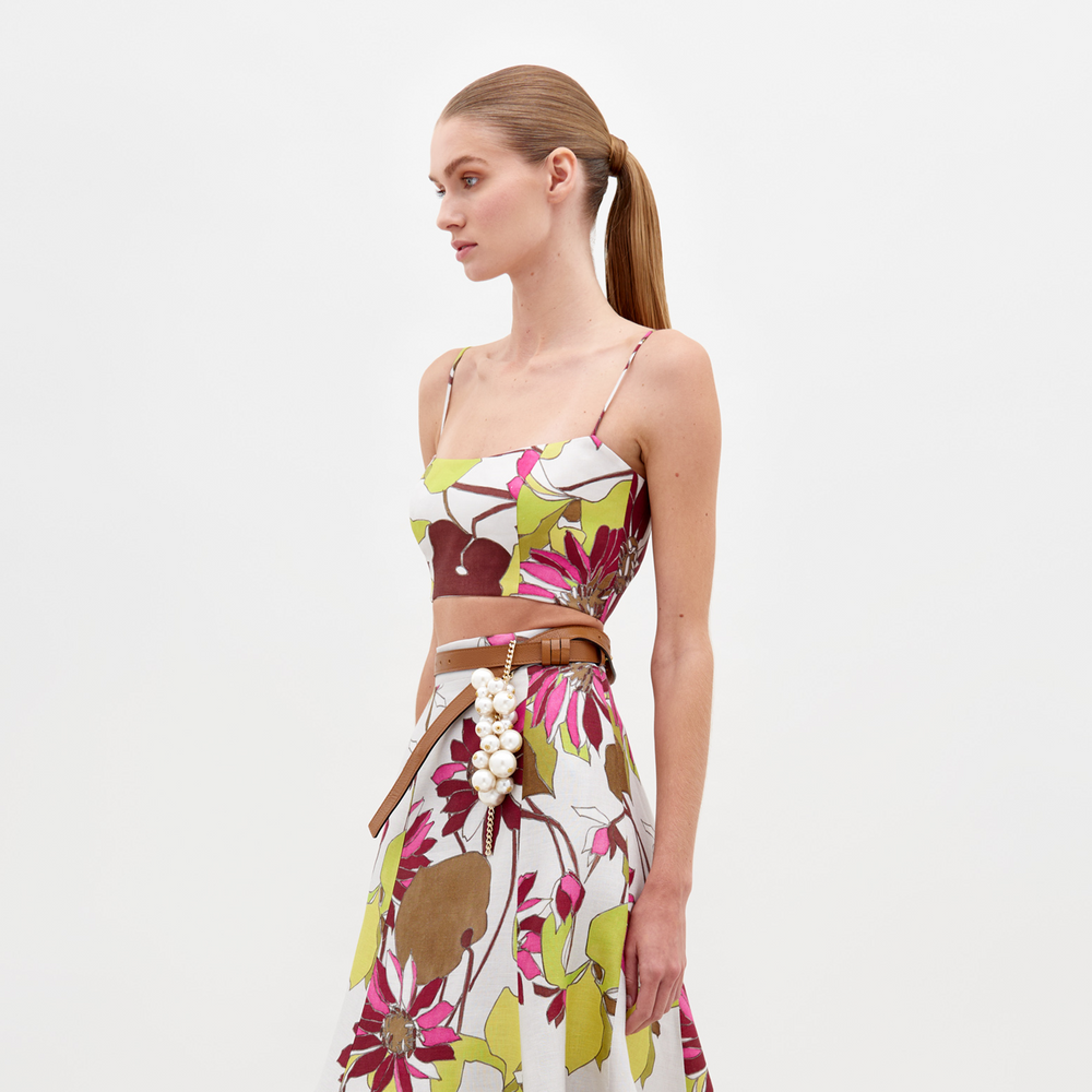 Woman in the Trini Top Botanical Multifloral paired with a pearl-embellished belt, side profile, against a plain white background. Mark your calendars: Orders placed by February 15th, 2025 will meet the guaranteed ship by date.