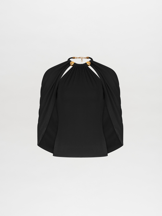 A person with tied-back hair wears a Tabatha Blouse Black with gold accents and a matching gold bracelet, standing against a plain white background. This stylish ensemble is available for pre-order now, with a ship by date of November 15th, 2024.