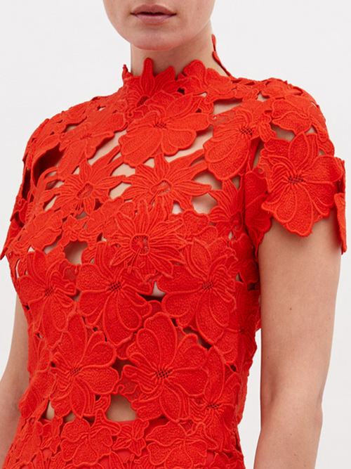 Person wearing a floor-length, red lace Taiana Dress Rouge with a high neckline and short sleeves, standing against a plain white background. Pre-order now to ensure delivery by the November 15th, 2024 ship-by date.