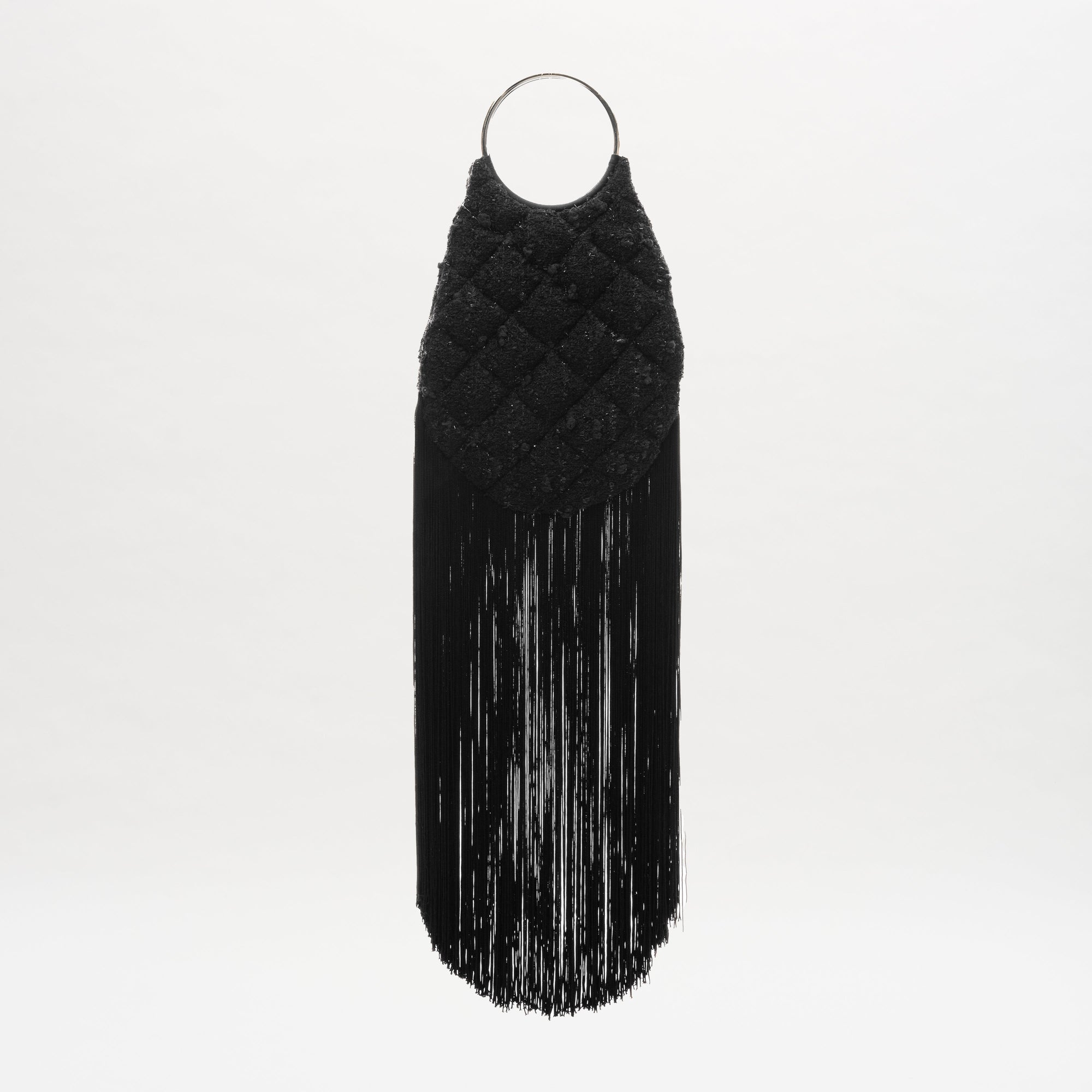 The Toblach Bag is a black quilted handbag made from Austrian fabric, with metallic top handles and long straight fringe at the bottom, shown against a plain white background.