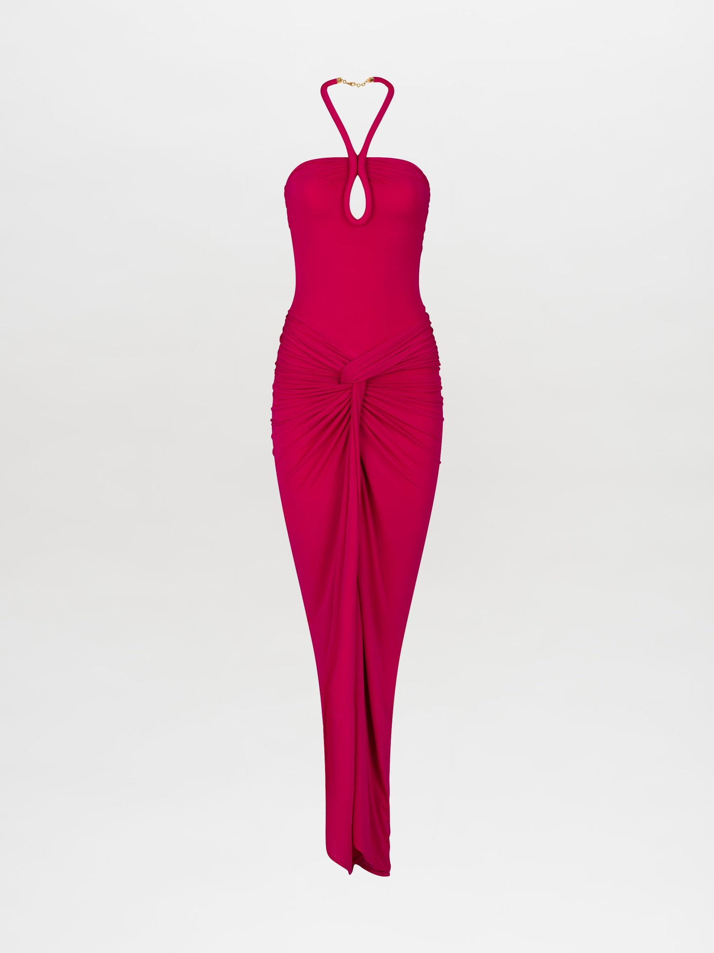 A woman stands in the Tori Dress Fuchsia, featuring a bright pink halter neck design with ruched detailing, paired with statement beige heels on a plain white background. This stylish ensemble is available for pre-order until February 15th, 2025.