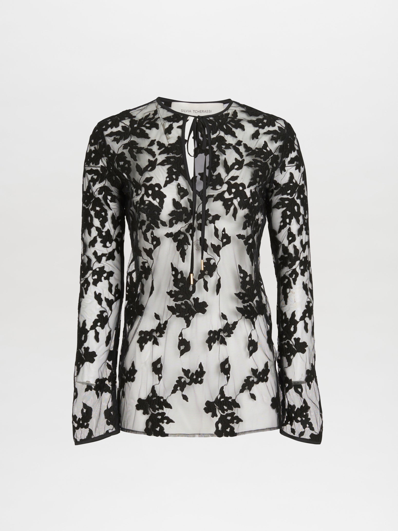 A long-sleeve, semi-sheer white Tosca Blouse Black Velvet featuring a black floral lace overlay and an abstract print keyhole tie neckline.