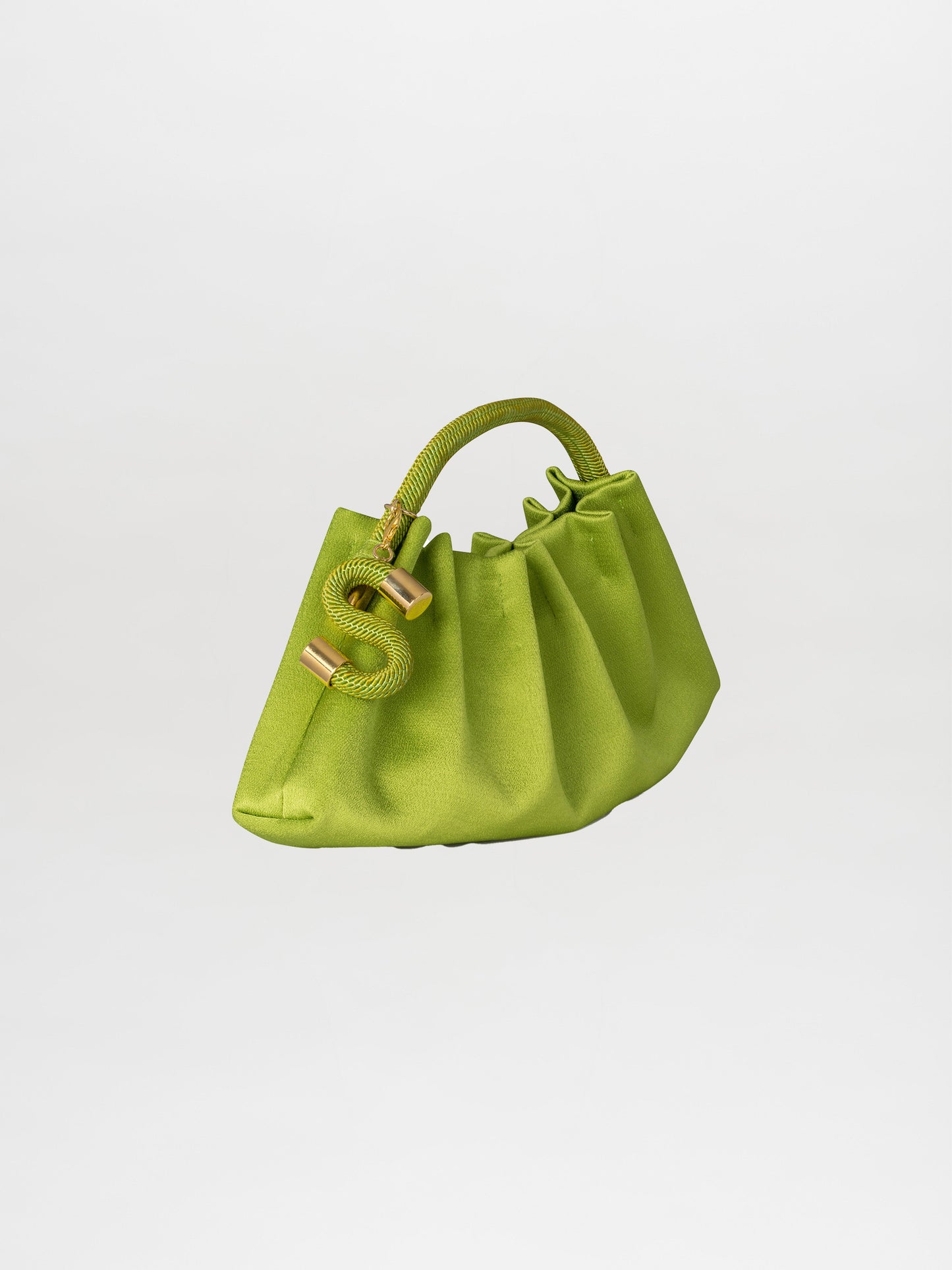 Introducing the Trapezius Clutch Lime: a pleated clutch crafted from crepe fabric, showcasing a vibrant green color and an organic, unique shape with a curved handle. It is elegantly adorned with gold accents and features a stylish S-shaped charm.