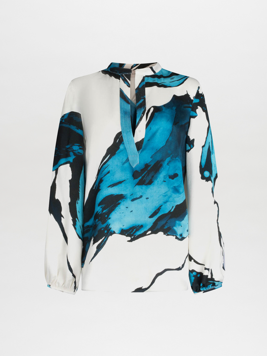 A white Triora Blouse Multi Abstract Waves with bold blue and black abstract print, featuring long sleeves and a V neckline with a tie.