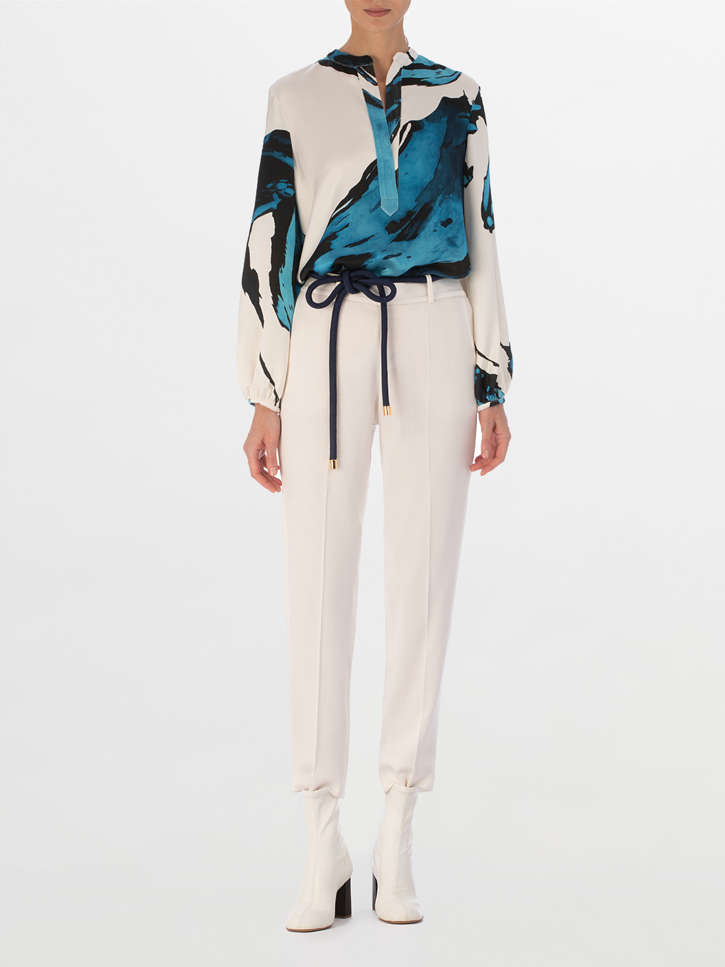A white Triora Blouse Multi Abstract Waves with bold blue and black abstract print, featuring long sleeves and a V neckline with a tie.
