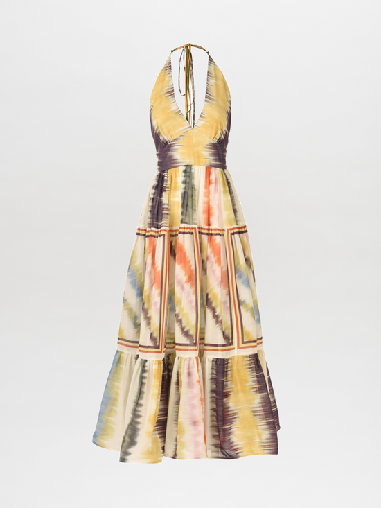 The Valerie Dress Multi Hazy Stripe is a sleeveless halter-neck midi dress featuring a vibrant multi hazy stripe tie-dye pattern and a charming tiered skirt.