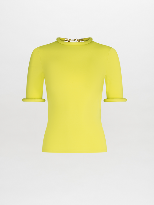 Venecia T-Shirt: A yellow short-sleeve top made from textured knit-like fabric, adorned with a gold clasp detail at the neckline reminiscent of metallic jewelry, showcased on a plain white background.