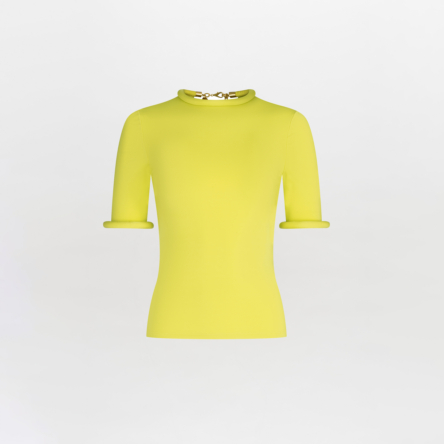 The Venecia T-Shirt is a bright yellow, short-sleeve shirt featuring a fitted silhouette with rolled cuffs. It has a round neckline with 3D detailing and a decorative clasp on a textured white background.