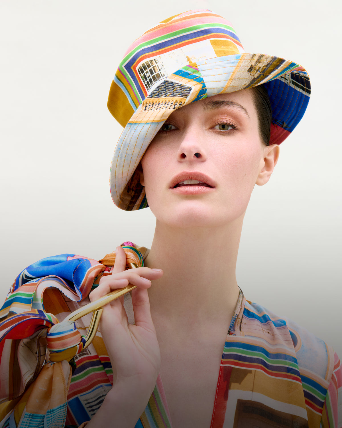 Person wearing a colorful striped hat and shirt against a plain background