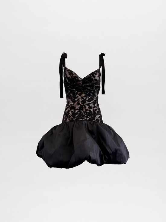 The Marguerite Dress Black features a strapless black lace and velvet design with a voluminous bubble hem and tied shoulder straps, showcased against a plain background.