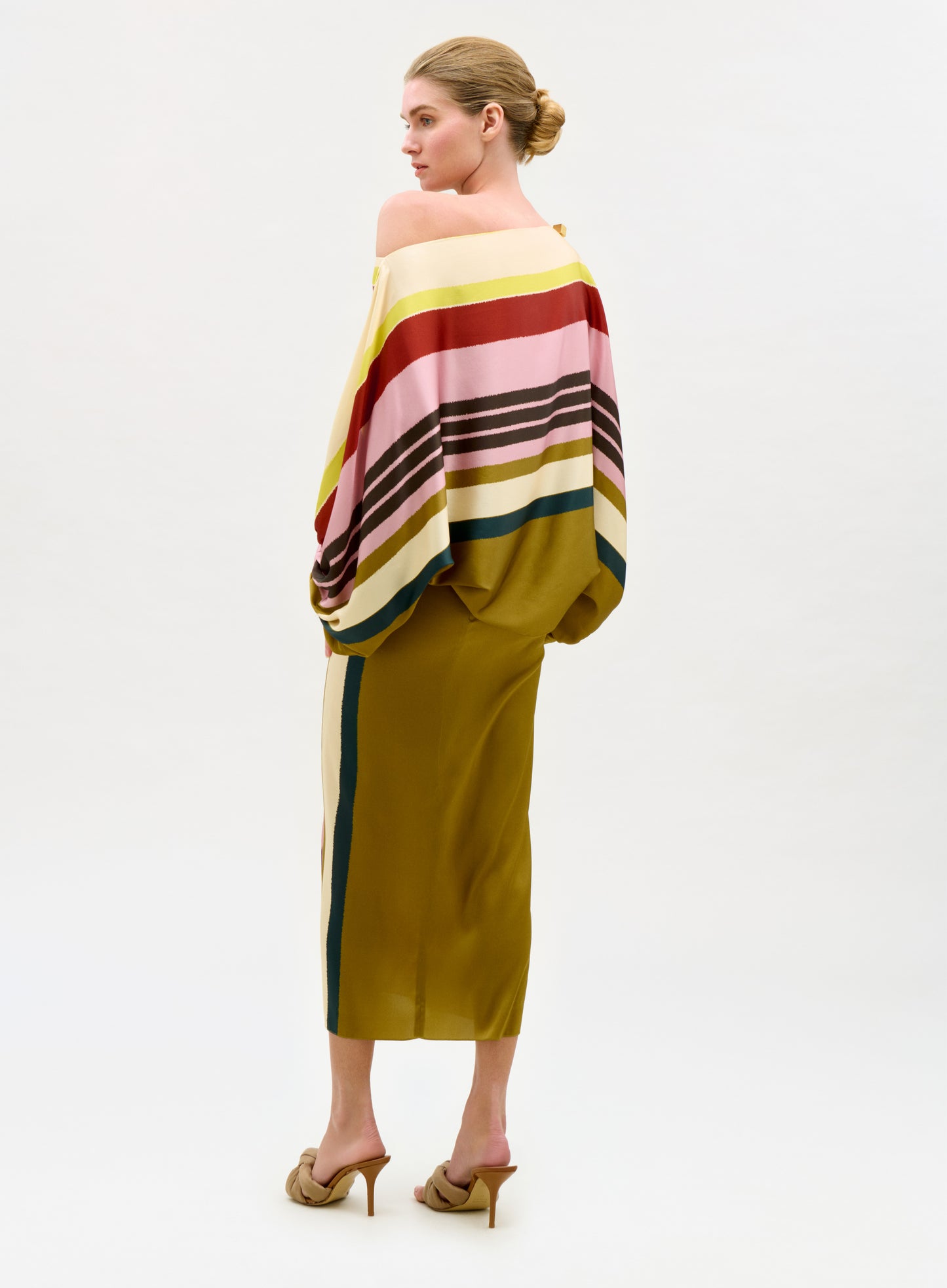 Woman wearing a colorful striped top and green skirt on a white background