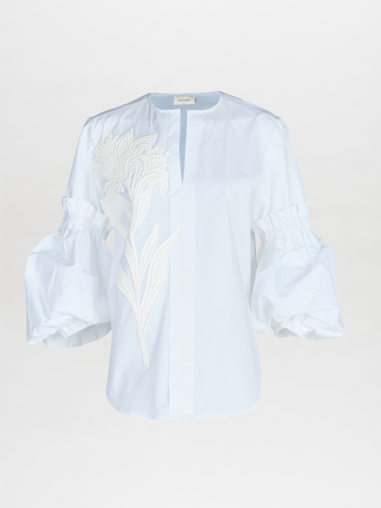 A Wenda blouse white with floral applique on the sleeves.