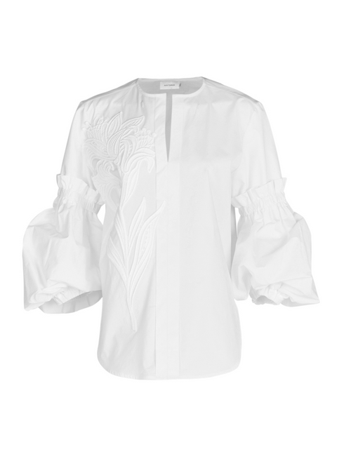 A Wenda blouse white with floral applique on the sleeves.