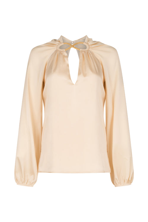 A Ximena Blouse Beige with a ruffled neckline and metallic detailing.