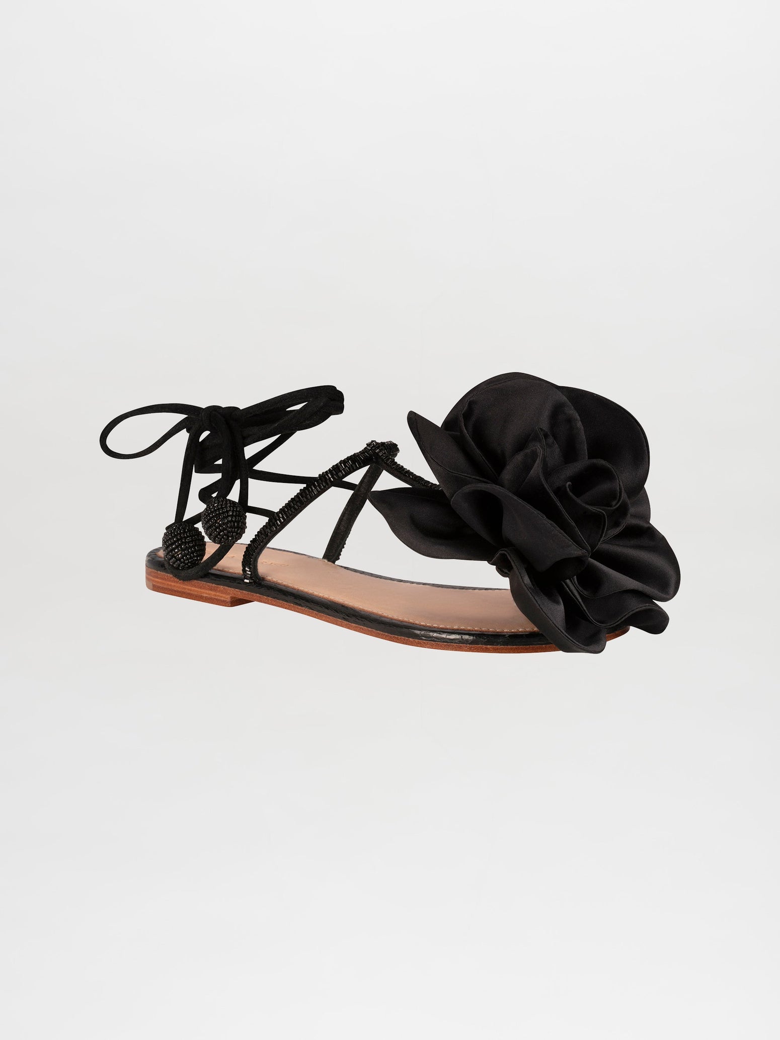 The Yoko Sandals Black feature thin straps, decorative knot details, and a prominent black fabric flower on the front. These elegant sandals have a flat sole and lace-up ankle ties. Available for pre-order now, they will ship by February 15th, 2025.