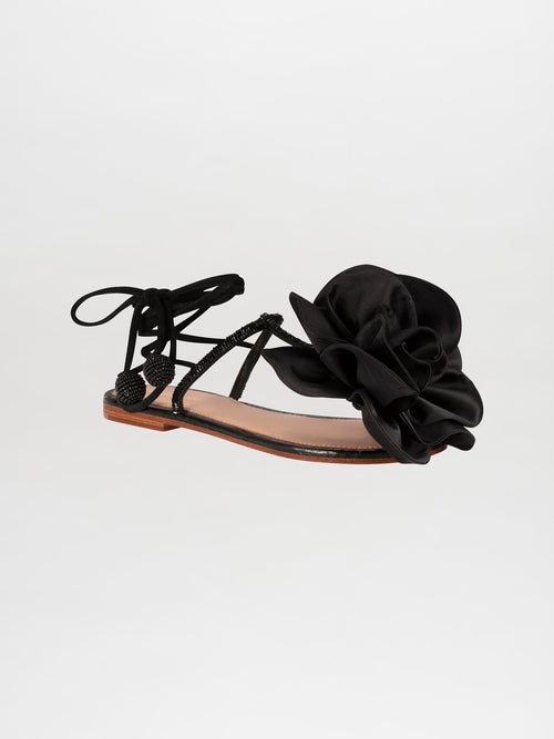 The Yoko Sandals Black feature thin straps, decorative knot details, and a prominent black fabric flower on the front. These elegant sandals have a flat sole and lace-up ankle ties. Available for pre-order now, they will ship by February 15th, 2025.