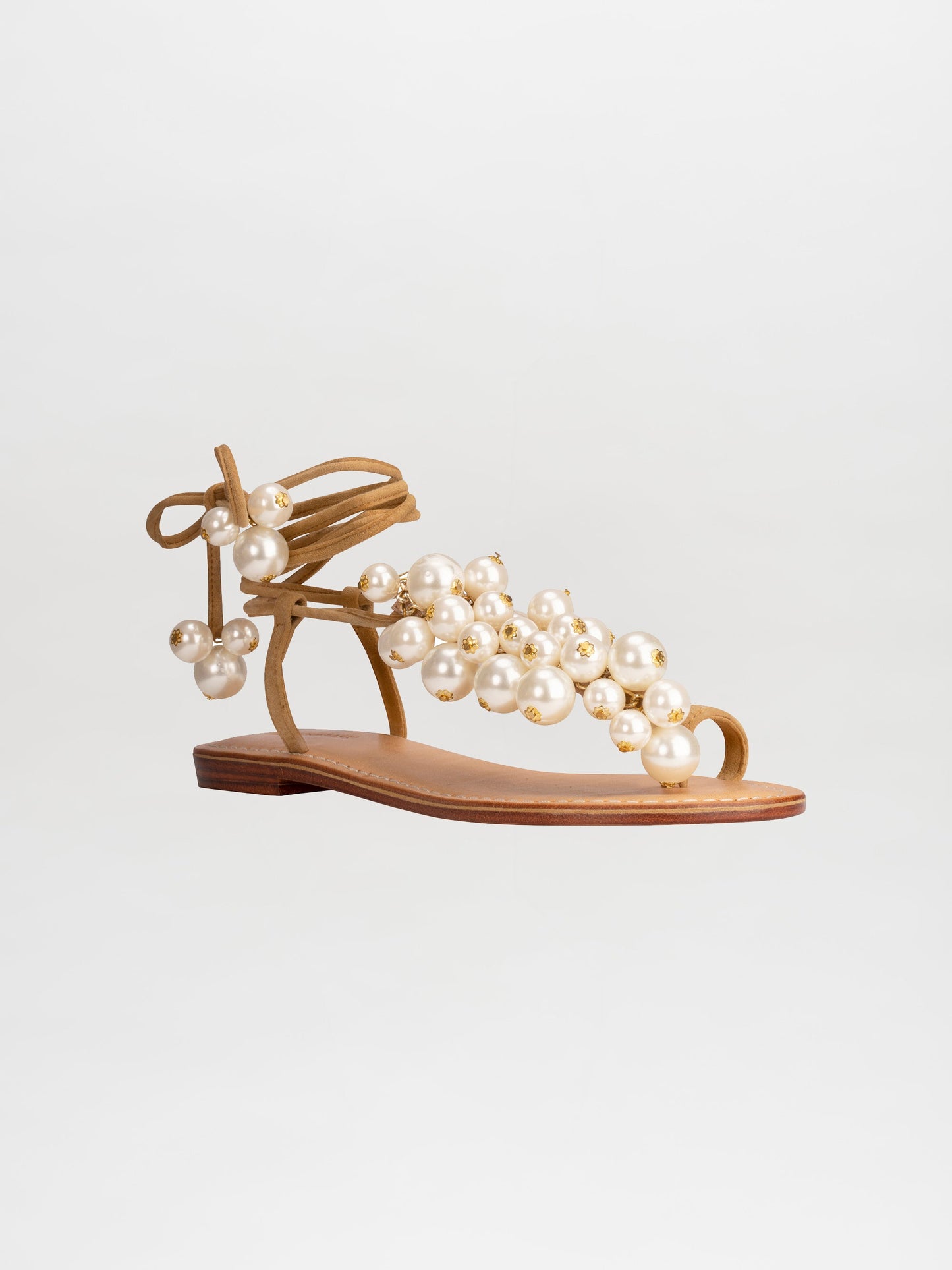 Presenting the Zaira Sandals Camel: a single tan sandal with a flat sole, adorned with multiple pearl-like beads and an ankle tie strap, displayed on a white background. Now available for pre-order; secure yours today and enjoy exclusive shipping by February 15th, 2025.