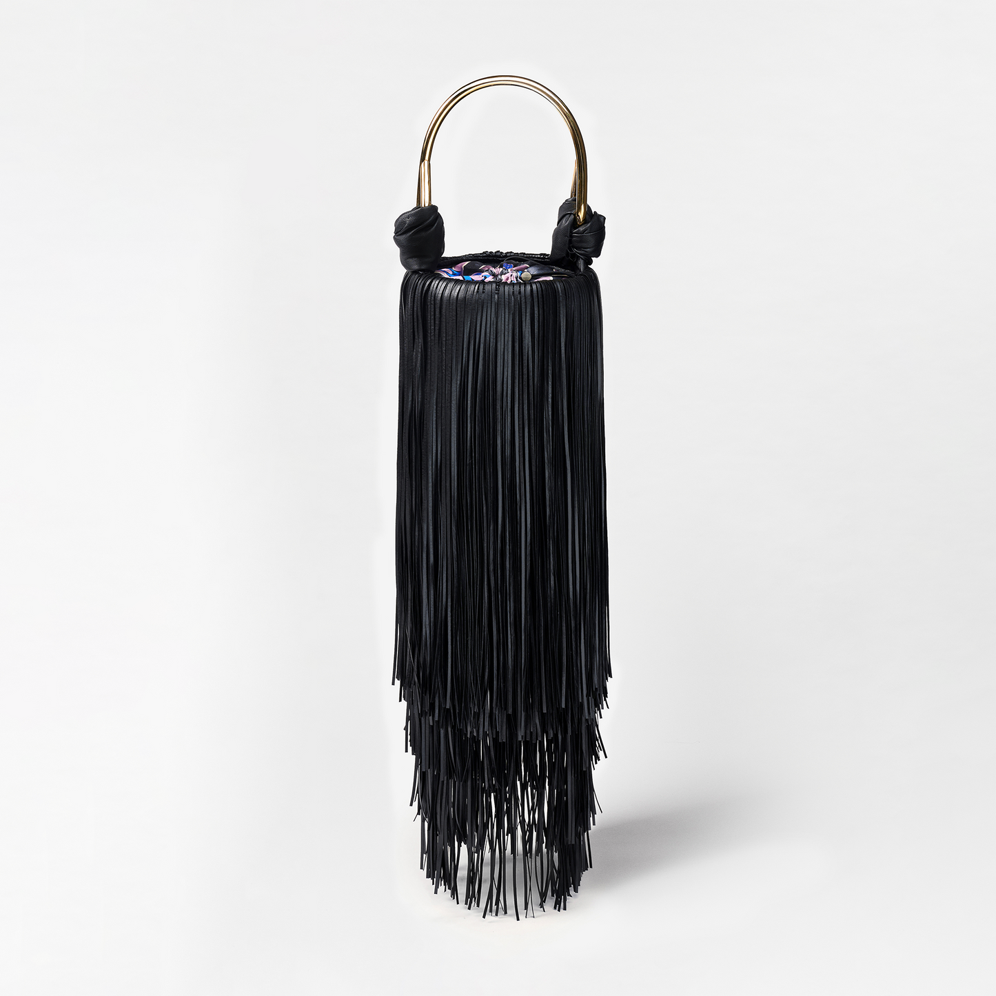 Black fringe handbag with gold handle on a light gray background