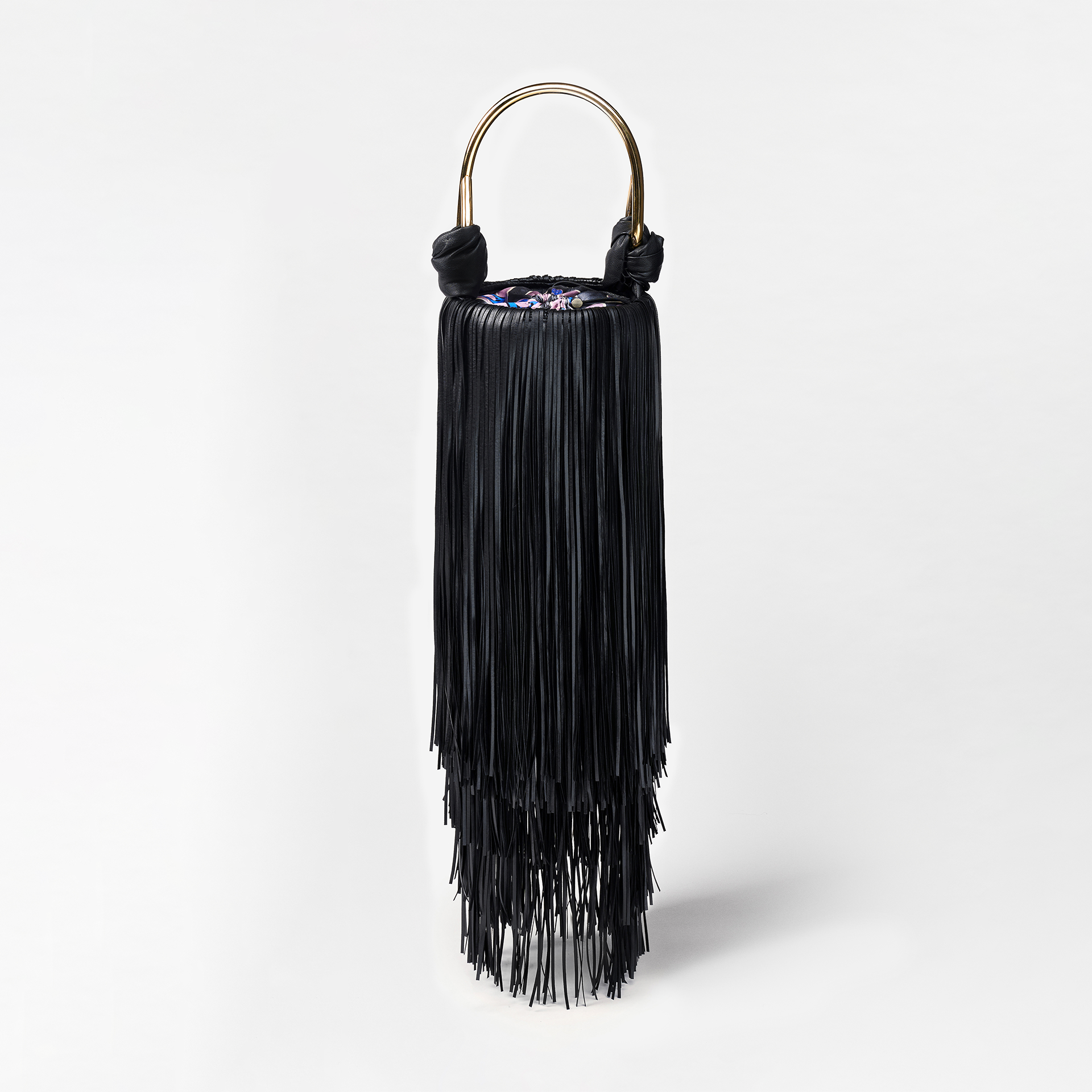 Black fringe handbag with gold handle on a light gray background