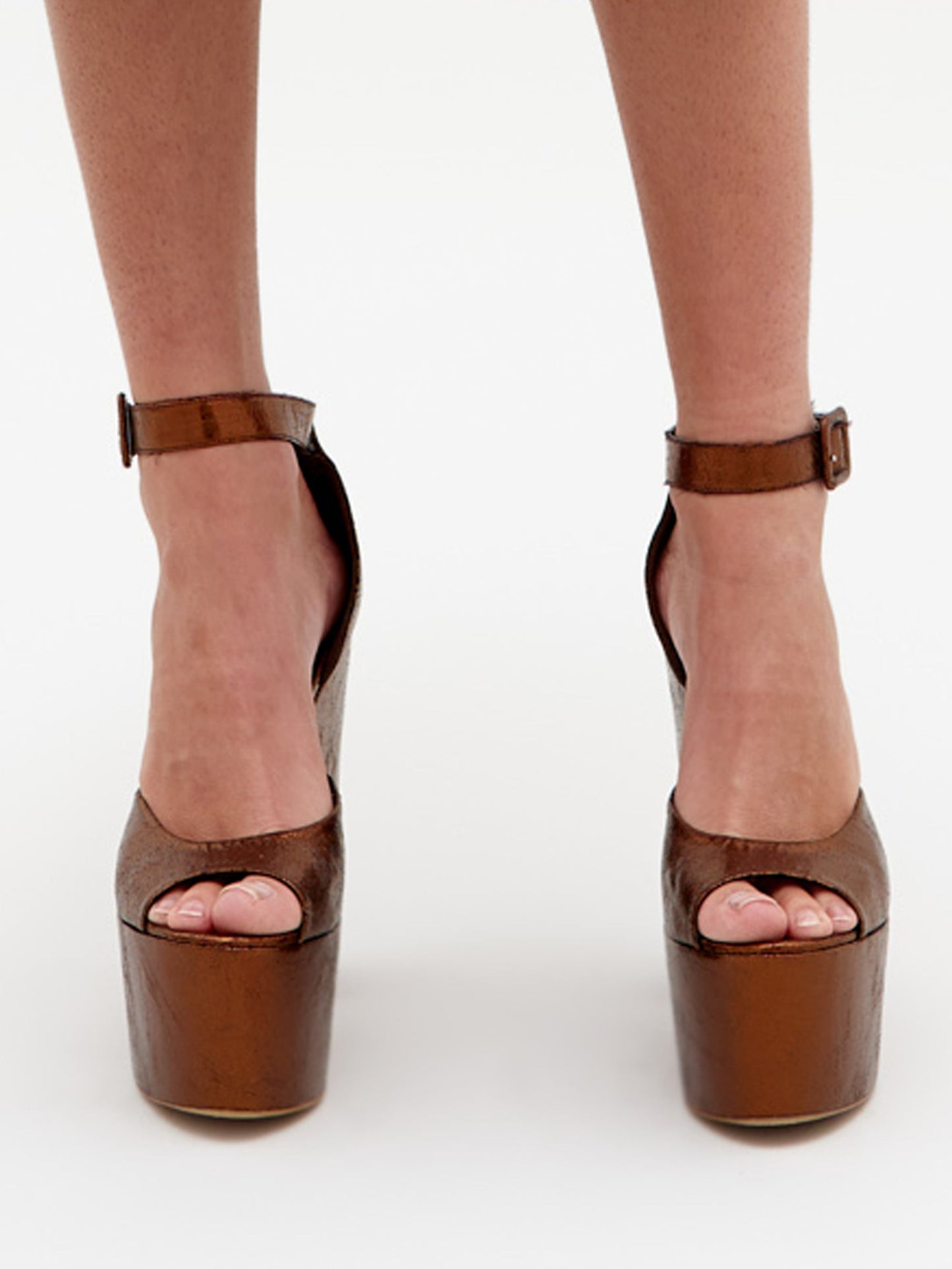 Wearing Oishi Heels Bronze platform heels with an ankle strap, a person pairs them perfectly with a light blue dress as they get ready for an elegant event, scheduled to ship by February 15th, 2025.