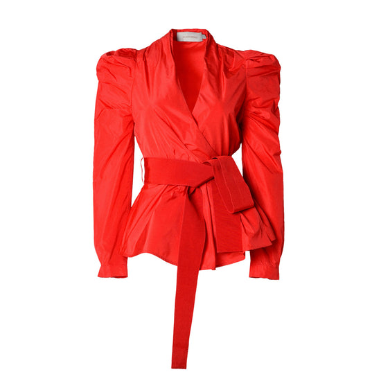 The Agnes Shirt Red is a vibrant scarlet women's blouse featuring puffed shoulders, a tailored waist, and a wide belt tied at the front.