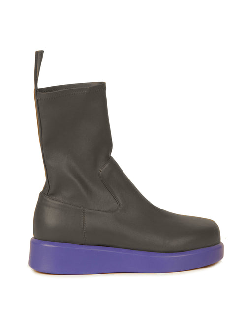 The Baia Boots Black Violet feature black ankle design in soft stretch calf leather, complemented by a thick, solid purple sole and a pull tab at the back, exuding fashion-forward appeal on a white background.