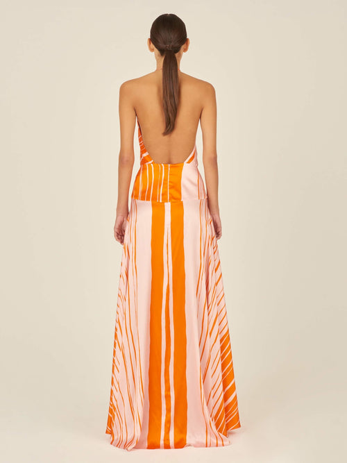 A flattering silhouette of an Agnese Dress Orange Pink with a halter neckline reminiscent of Silvia Tcherassi designs.