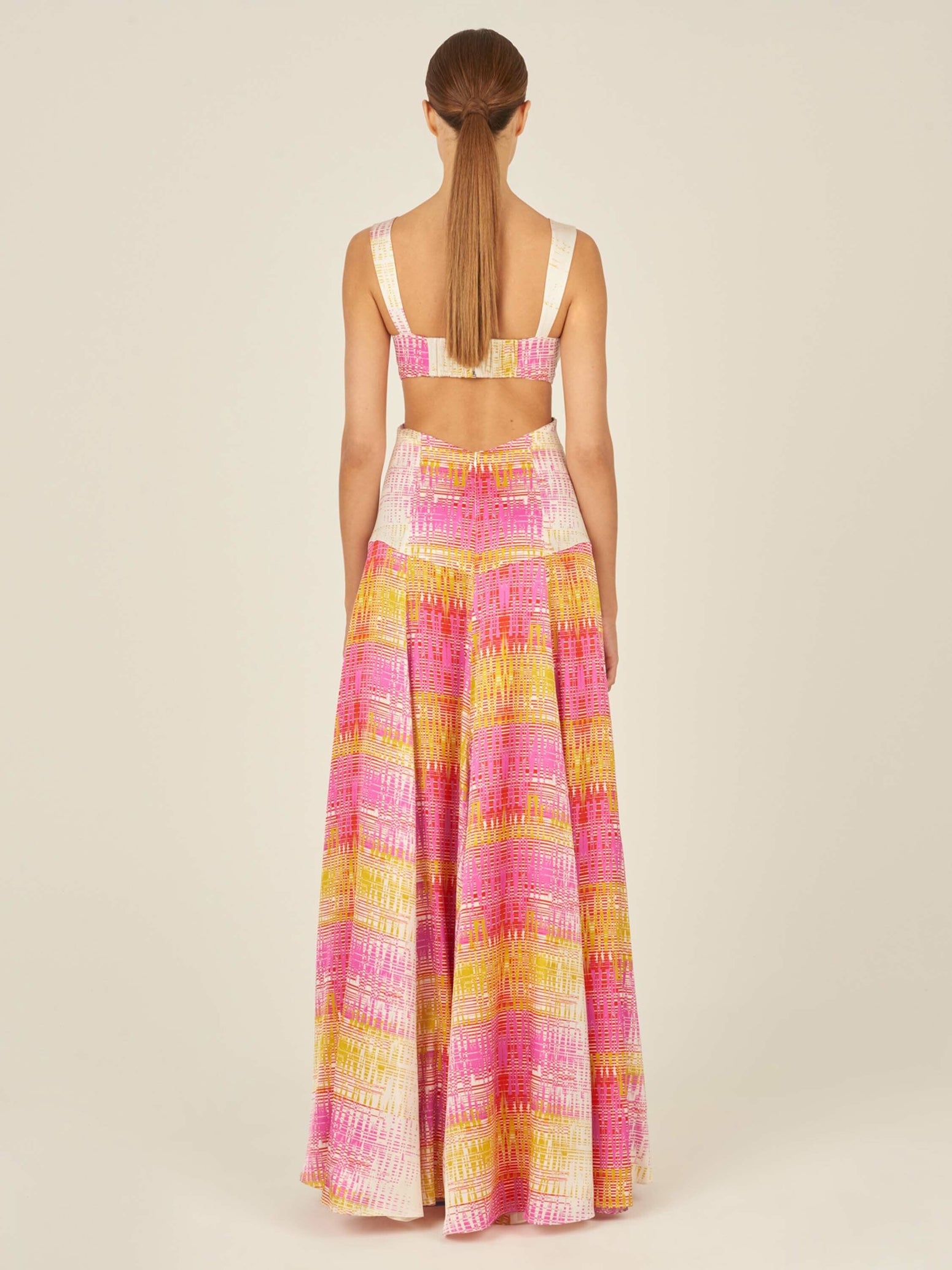 A Cervo Dress White Digital with a colorful, digital electric print in pink, yellow, and white tones, featuring cutout details at the waist and a front knot detail.