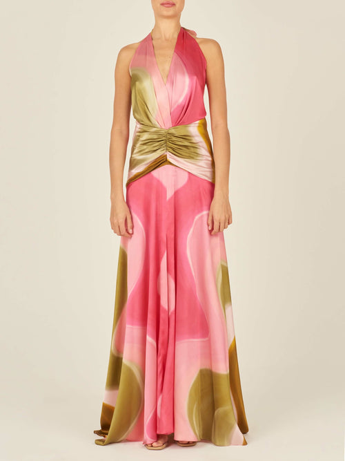 A sleeveless, floor-length Dafne Dress Olive/Pink with a halter v-neckline, in a pink, white, and green abstract pattern. The waist is accentuated with a gathered detail.