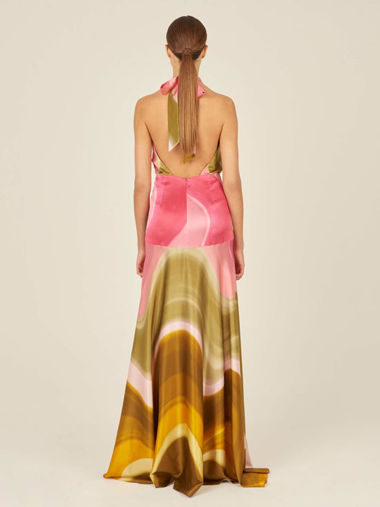 A sleeveless, floor-length Dafne Dress Olive/Pink with a halter v-neckline, in a pink, white, and green abstract pattern. The waist is accentuated with a gathered detail.