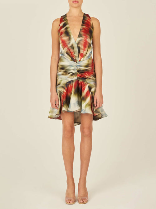 The Elettra Dress Multi Linear from the Pre Fall 2023 collection is a sleeveless silk mini dress with a multicolor, abstract pattern. It features a V-neckline, ruched waist, and a flared, ruffled hemline.