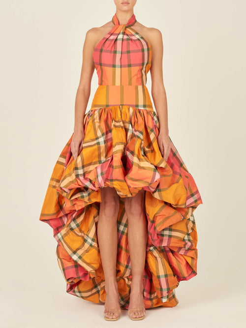 A mannequin dressed in an orange plaid taffeta garment with a large, ruffled skirt section, showcasing an Eloina Dress Ultra Orange.