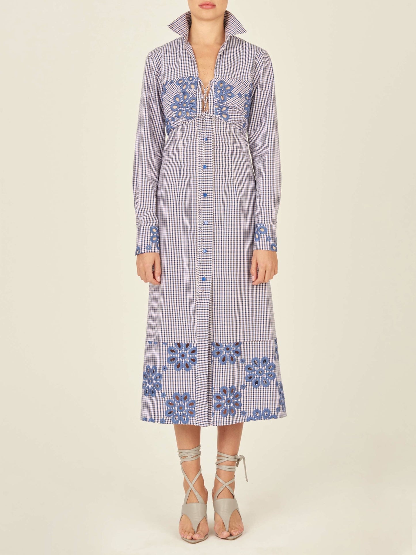 The Ganzoni Dress Navy Floral is a long-sleeve, button-down dress with a collar, featuring a blue and white checkered pattern and blue floral designs. This item is part of our Final Sale and is not eligible for return or exchange.