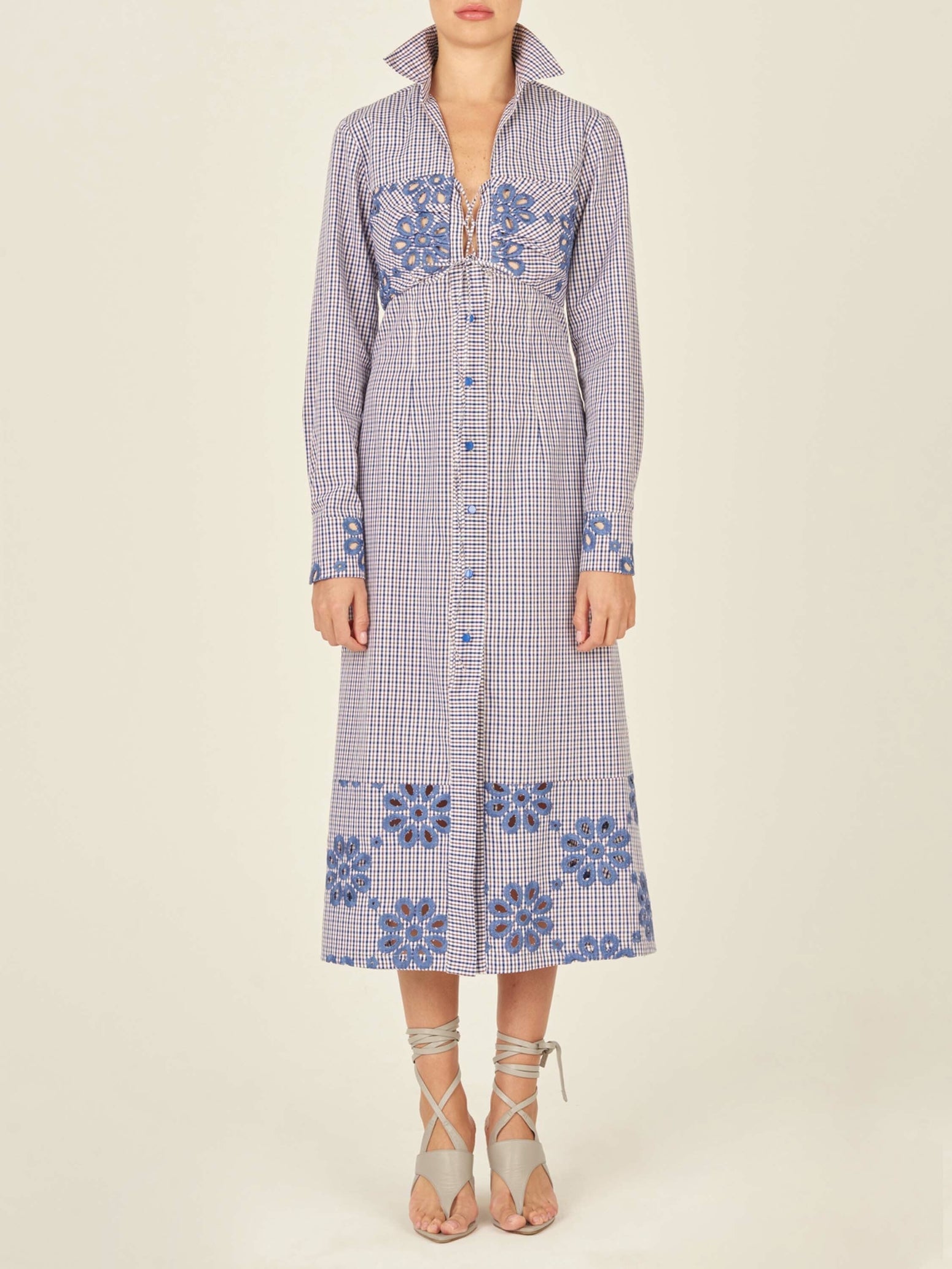 The Ganzoni Dress Navy Floral is a long-sleeve, button-down dress with a collar, featuring a blue and white checkered pattern and blue floral designs. This item is part of our Final Sale and is not eligible for return or exchange.