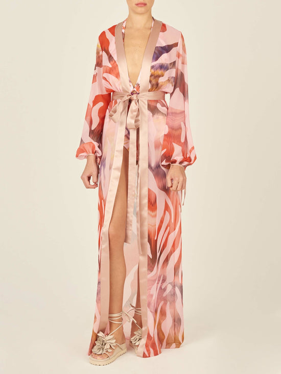 Long-sleeved, pink, and beige patterned robe with a sash belt and wide lapels. The Magdalena Dress Blush Prismatic features abstract zebra print brushstroke designs and tie detailing on the sleeves.