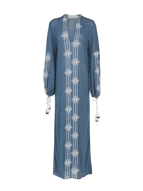 A navy blue, long-sleeved Mayfair Tunic Navy Embroidered with a V-neckline featuring white geometric embroidery down the front and on the sleeves, finished with tasseled ties at the cuffs.