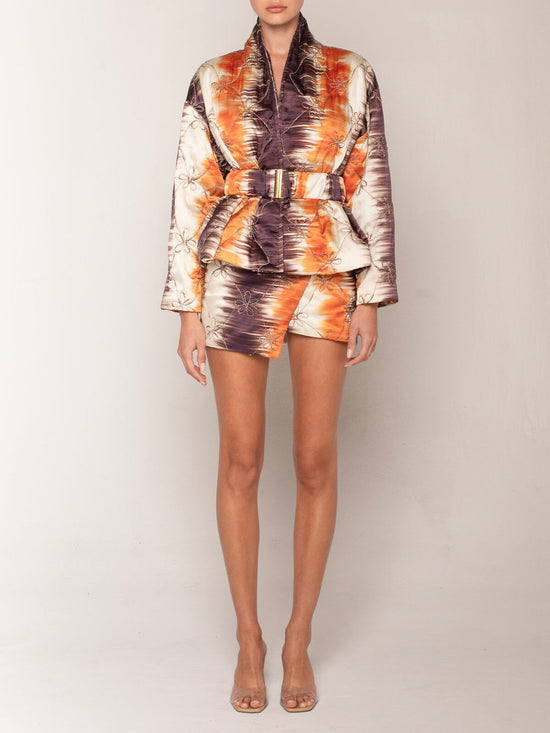 The Aimee Skort Mulberry Orange Hazy is a high-waisted, multicolored skort featuring an abstract floral pattern and an asymmetric hemline, perfect for Resort 2023.