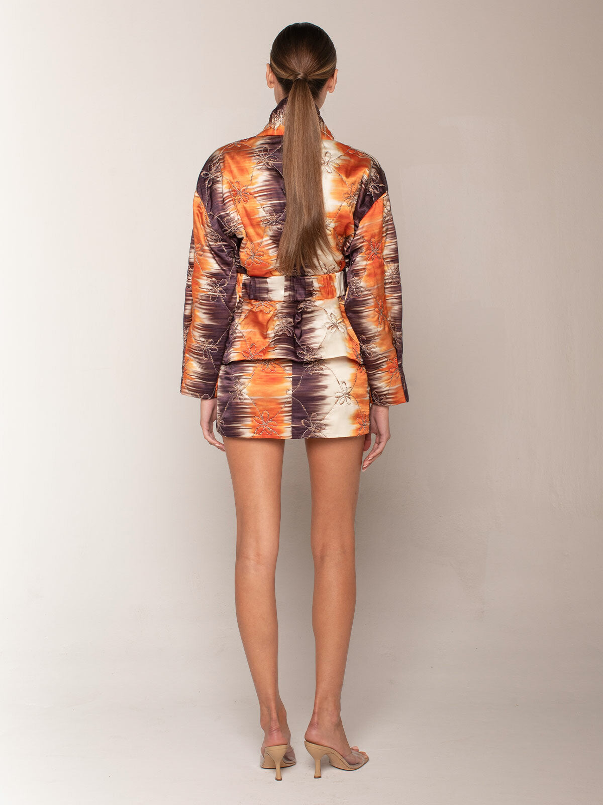 The Aimee Skort Mulberry Orange Hazy is a high-waisted, multicolored skort featuring an abstract floral pattern and an asymmetric hemline, perfect for Resort 2023.