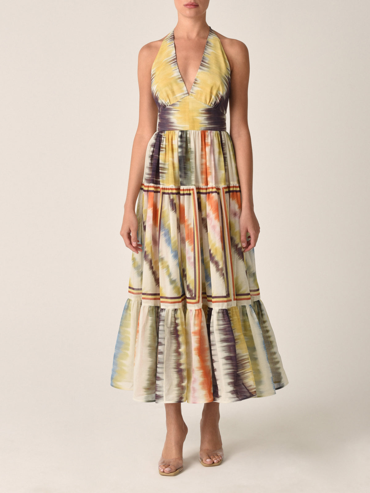 The Valerie Dress Multi Hazy Stripe is a sleeveless halter-neck midi dress featuring a vibrant multi hazy stripe tie-dye pattern and a charming tiered skirt.