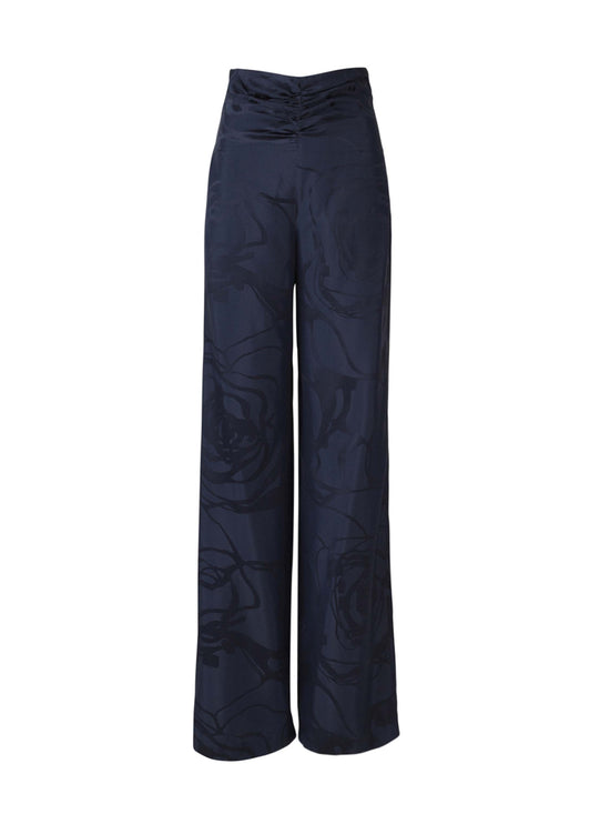 Casey Pant Navy Jacquard, these high-waisted, wide-leg pants featuring a subtle floral pattern in luxurious jacquard fabric and a gathered waistband detail.