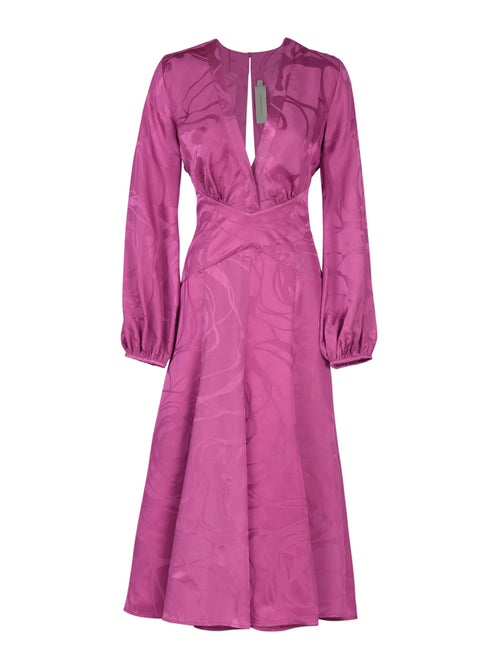 A long-sleeved, floor-length Kathryn Dress Magenta Orchid Jacquard with a V-neck and criss-cross bodice, featuring a subtle jacquard pattern and a tag near the neckline.